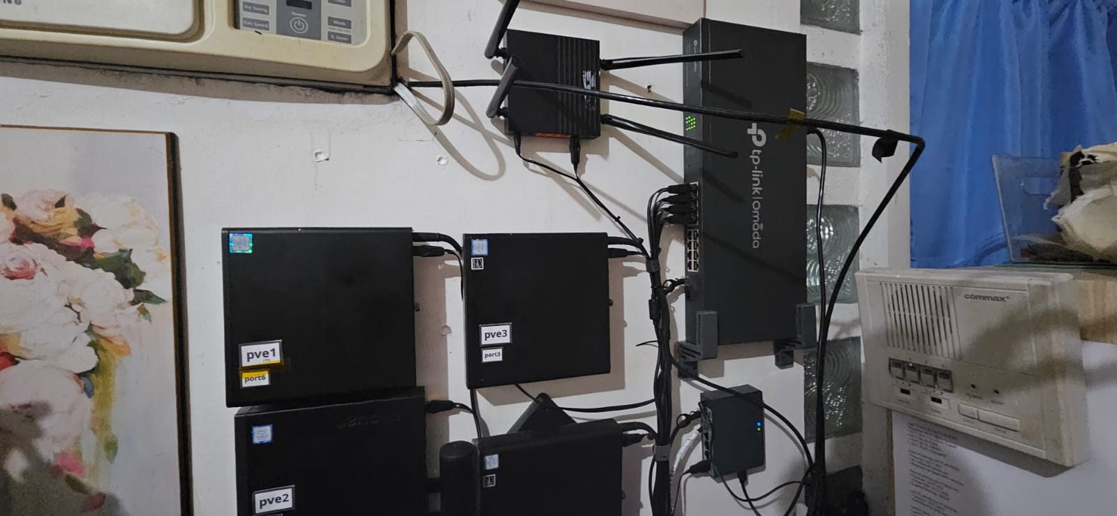 Wall-mounted cluster overview showing labeled pve nodes, switch, router, and AP